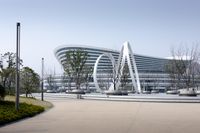 a large building that is sitting next to a park by some water features and trees