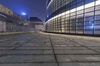 the view down an alley looking into a building at night time with glass walls and windows