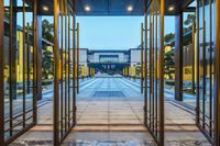 a large hallway that has glass doors leading to it with columns on each side of it