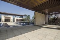 the entrance of a house has a round shaped fountain and some trees around it,