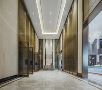 a hallway with gold colored glass and glass doors, large mirrors, and a tile floor