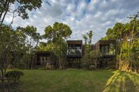 a house in the jungle on the grass and the trees behind it are seen in this photograph