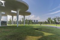 a modern building sits in the green area next to the road by a park with trees and grass