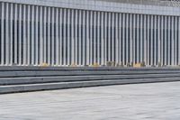 a man standing by a building with one foot on the ground and two feet up on a cement wall