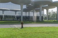 a fire hydrant is outside of an office building with many columns above it and grass in front