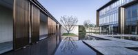 a reflection of trees in water is seen through windows at the entrance to an office complex