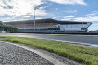 the outside of a sports stadium with many seats sitting on the track as well as grass and plants growing below