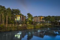 three cabins sit at the edge of a river at night, while illuminated by floodlights and a rain cloud