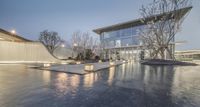 the water is reflecting off of the wet surface in the middle of a courtyard with illuminated benches,