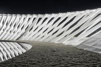 an abstract sculpture at night near the water's edge is a curving white piece