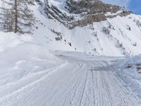 snow covered road going through the mountains, with a lone skier skiing past on it
