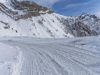 snow covered road going through the mountains, with a lone skier skiing past on it
