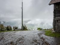 a view of a wet road in the countryside during the day time, with low clouds