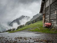 a view of a wet road in the countryside during the day time, with low clouds
