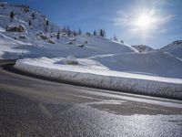 a person that is snow skiing in the snow and some grass, near mountains and a road