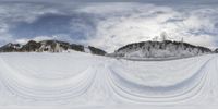 a person on skis goes down a snow slope in the mountains behind them, and a very large sky with white clouds and hills beyond