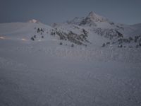 a man skiing down a snow covered mountain on a trail with a lodge in the distance
