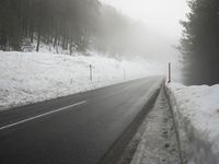 a snowy street with trees and a white fence near by, foggy scene, winter