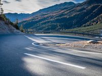 road next to a mountain under a cloudless sky with the sun coming down in the middle