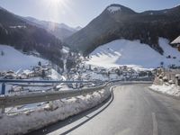 a view from the side of a long mountain road in a town with snow covered mountains