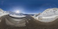 a mirror image with the sun in it's middle and snow covered hills behind it