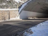 a motorcycle is driving through the tunnel in the snow, underneath which a fence and snowy slope is covered with snow