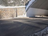 a motorcycle is driving through the tunnel in the snow, underneath which a fence and snowy slope is covered with snow