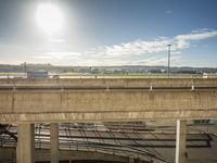 a car parked on an overpass near a highway with a train going underneath it