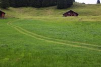 there is a little cabin on the hill with green grass in it near a path