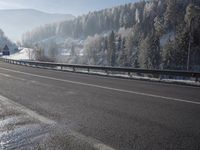 the red motorcycle is driving along the roadway with trees around it in winter time on a cold day