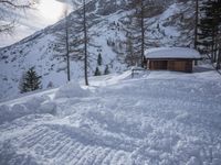 there is a small cabin near a mountain on the snow covered slope of snow hill