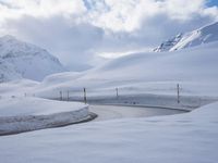 a snow covered road is going through the snowy mountains with a sign pointing right to it