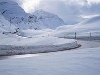 a snow covered road is going through the snowy mountains with a sign pointing right to it