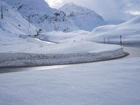 a snow covered road is going through the snowy mountains with a sign pointing right to it