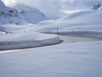 a snow covered road is going through the snowy mountains with a sign pointing right to it