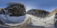 a 360 - angle picture of the snow covered road next to a large hill and wooded area