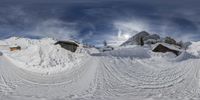 the snowy mountain slope is covered in snow next to cabins and snowboards, under a cloudy blue sky