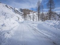 a snowy dirt road on a clear day with mountain in the background with skis