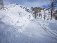 a snowy dirt road on a clear day with mountain in the background with skis