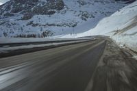 a blurry view of the road and mountains in wintertime, with motion blurring around the vehicle