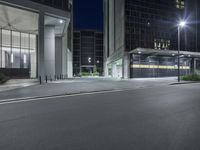 night scene with empty street, illuminated buildings and lights in background area at corner of road