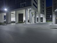 night scene with empty street, illuminated buildings and lights in background area at corner of road