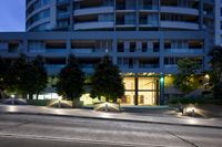 an image of a building in the evening with some trees around it and lights on