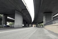 a road underpass with an overpass in the background and a building in the background