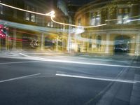 an image of a city intersection at night time and light trails bluring the camera