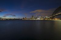 the view of sydney, from across the water at night with city lights reflecting in the water