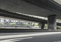 a road under an overpass with a street sign in front of it and trees in the distance