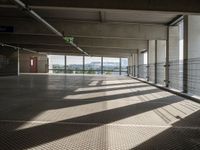 a corridor with many windows and signs in the sunlight behind them, with an empty walkway leading up to a window