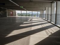 a corridor with many windows and signs in the sunlight behind them, with an empty walkway leading up to a window