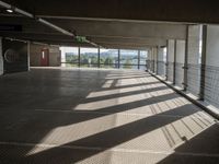 a corridor with many windows and signs in the sunlight behind them, with an empty walkway leading up to a window